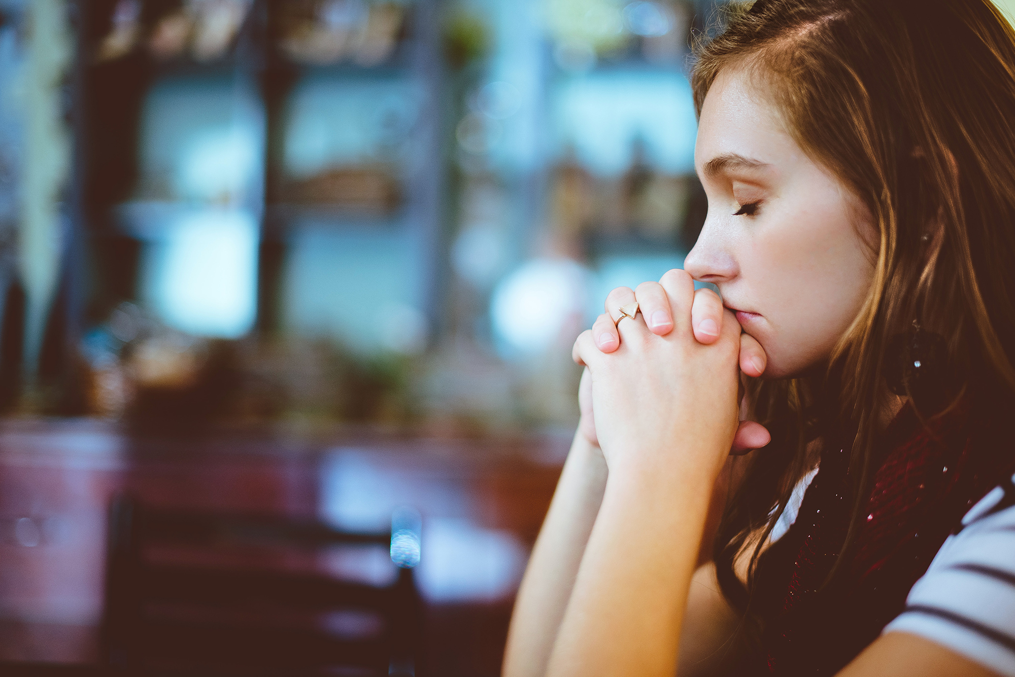A Girl sits and prays with her eyes closed